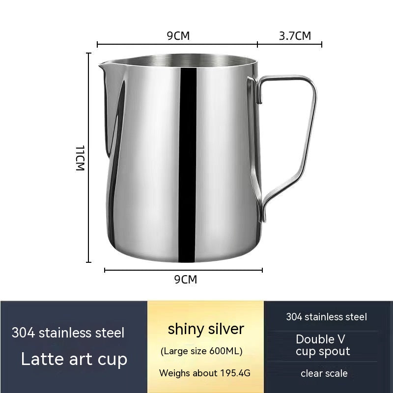 Matte black milk pitcher on a wooden counter beside coffee beans