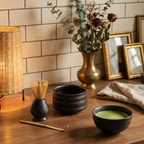 Matcha tea ceremony set with dark chawan bowl and bamboo whisk on a cozy home counter