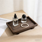 Angled view of the footed solid wood tray with two glass bottles