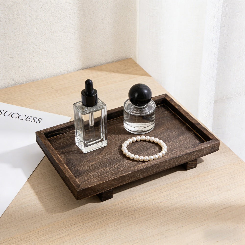 Angled view of the footed solid wood tray with two glass bottles