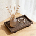 Footed solid wood tray holding a frosted reed diffuser and a pearl bracelet